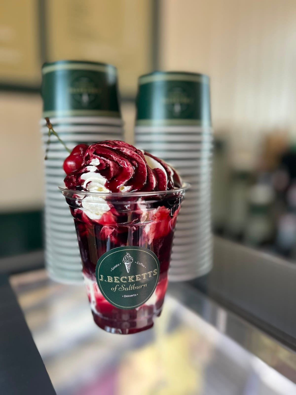 A cherry sundae topped with cream on the J.Becketts counter
